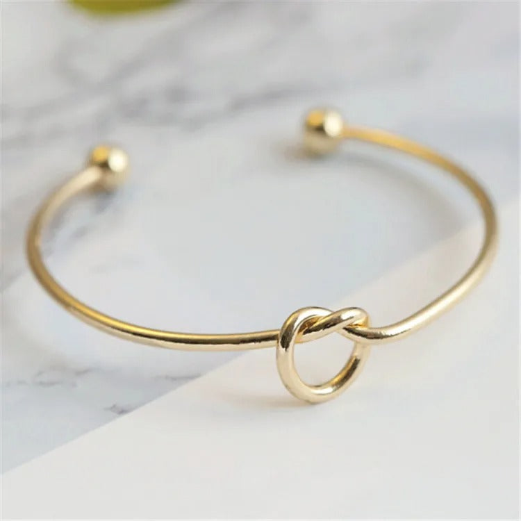Women's gold twist bangle styled with luxury accessories