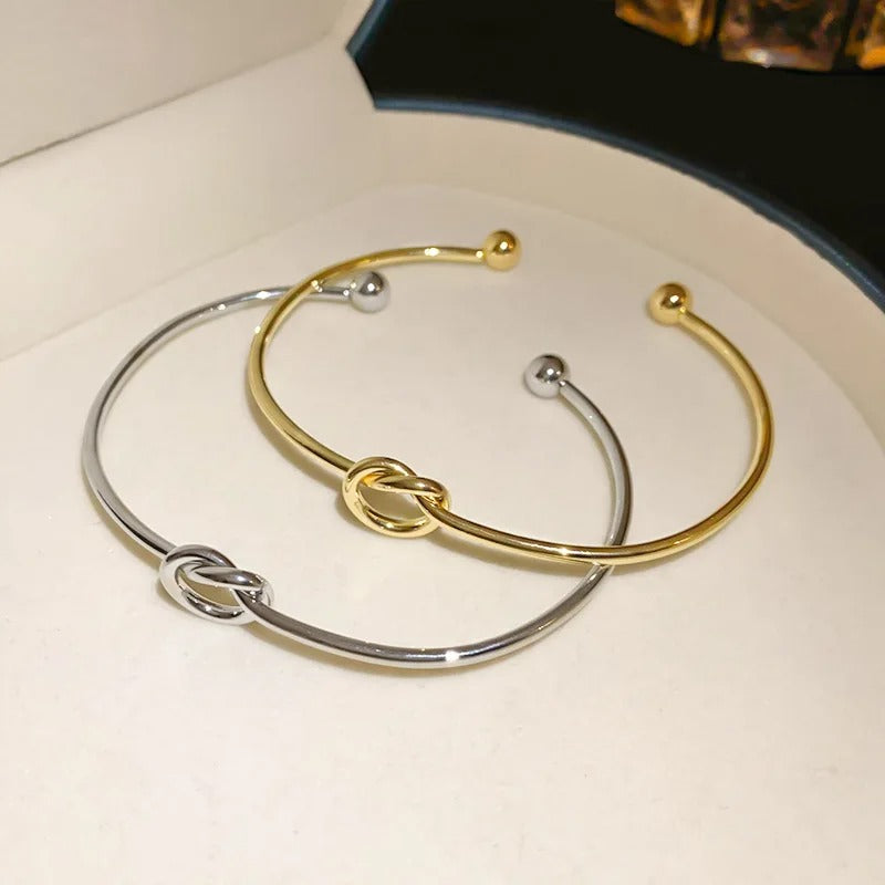 A stack of women's gold bracelets featuring the Velmeera rope cuff